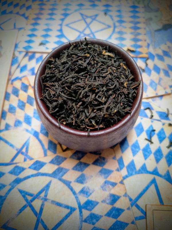 Dry tea leaves in a ceramic bowl on a patterned surface